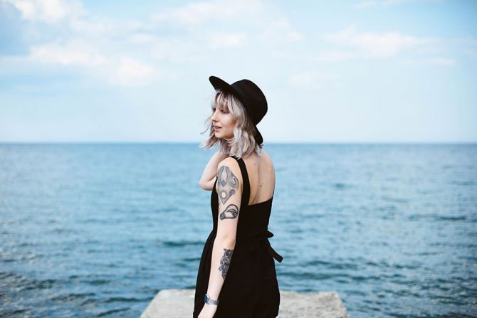 Jeune femme blonde tatouée au bord de mer.