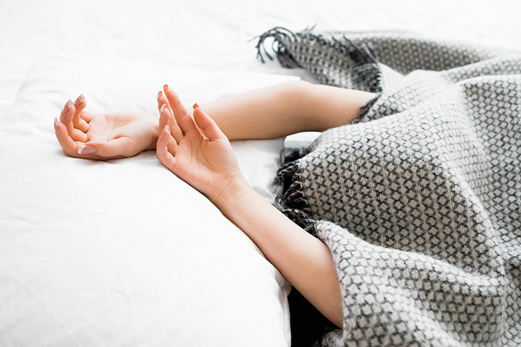Jeune femme qui dort le visage complètement recouvert par des couvertures.