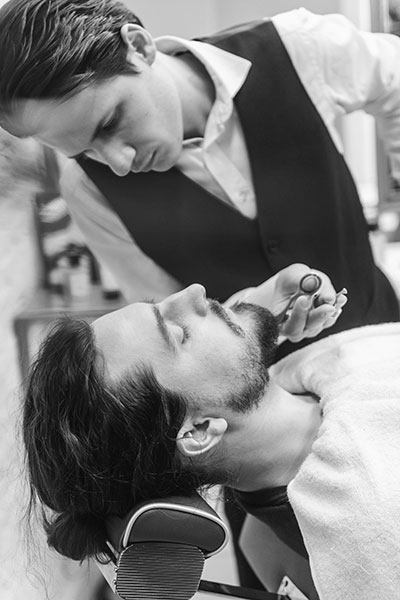 Photo d'un homme en train de se faire tailler la barbe par un barbier professionnel.