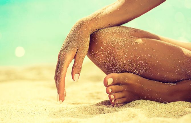 Jambe et bras de femme de femme bronzée sur une plage.