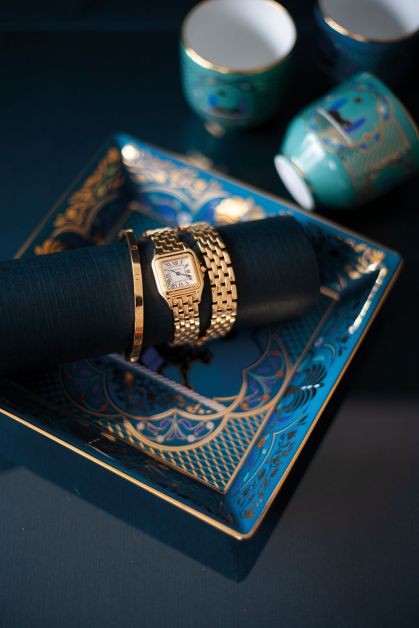 Armband LOVE, klein model in 18 karaats geel goud, horloge met dubbele band in 18 karaats geel goud, beide Cartier. Vide-poche en kopjes Panthère de Cartier in blauw Limoges-porselein met arabesken.