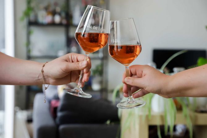 Deux mains tenant deux verres de vin rosé