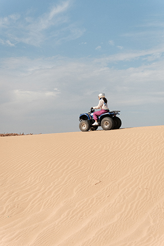 Jeune femme sur un quad dans les dunes.