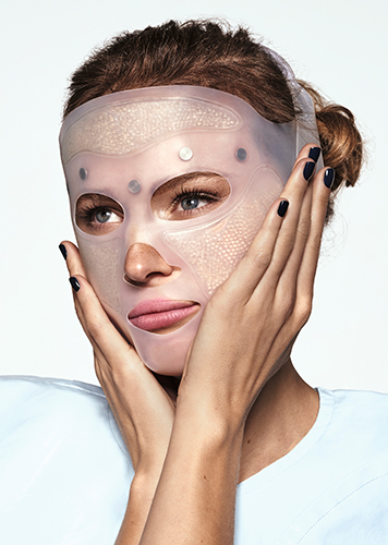 Jeune femme testant un masque LED sur son visage.