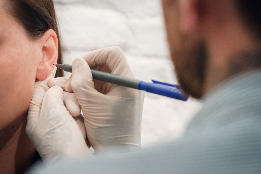 Met stift duidt Colby het eerste piercingpunt aan: in een natuurlijk kuiltje komt een eenvoudig steentje voor een subtiele glinstering.