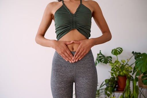 A woman holds her hands to her stomach, illustrate gut health